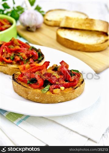 Bruschetta with roasted tomatoes, peppers, garlic, onions and parsley in a plate on a kitchen towel on the background of wooden boards