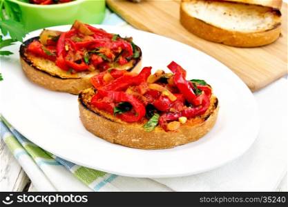 Bruschetta with roasted tomatoes, peppers, garlic, onions and parsley in a plate on a towel on the background of wooden boards