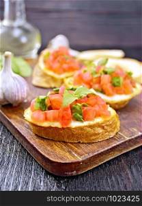 Bruschetta with tomato, basil and spinach on a plate, vegetable oil in a decanter against a dark wooden board