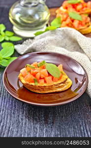 Bruschetta with tomatoes and basil in a plate, napkin and vegetable oil in a decanter on wooden board background