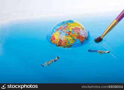Brush and little globe with floating figurines around in water