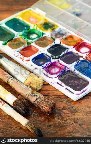 Brush and paint. Set of watercolors and different brushes for painting on wood vintage palette