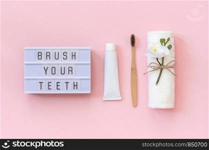Brush your teeth - Light box text and natural eco-friendly bamboo brush for teeth, towel, toothpaste tube. Set for washing on pink background. Concept dental health care Top view Flat lay.. Brush your teeth - Light box text and natural eco-friendly bamboo brush for teeth, towel, toothpaste tube. Set for washing on pink background. Concept dental health care Top view Flat lay