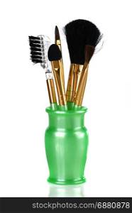 brushes for makeup in green vase on a white background
