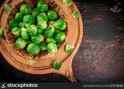Brussel cabbage in a basket on a cutting board. Against a dark background. High quality photo. Brussel cabbage in a basket on a cutting board.