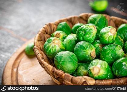 Brussel cabbage in a basket on a cutting board. Against a dark background. High quality photo. Brussel cabbage in a basket on a cutting board.