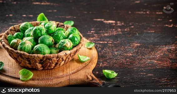 Brussel cabbage in a basket on a cutting board. Against a dark background. High quality photo. Brussel cabbage in a basket on a cutting board.