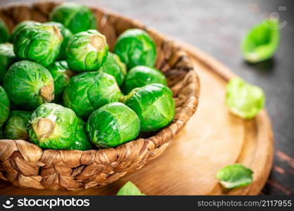 Brussel cabbage in a basket on a cutting board. Against a dark background. High quality photo. Brussel cabbage in a basket on a cutting board.