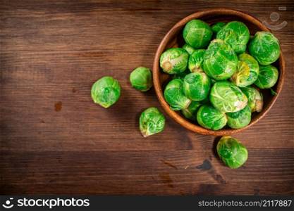Brussels cabbage in a bowl on the table. On a wooden background. High quality photo. Brussels cabbage in a bowl on the table.