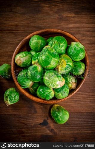 Brussels cabbage in a bowl on the table. On a wooden background. High quality photo. Brussels cabbage in a bowl on the table.