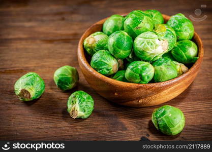 Brussels cabbage in a bowl on the table. On a wooden background. High quality photo. Brussels cabbage in a bowl on the table.