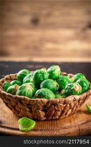 Brussels sprouts in a basket on the table. On a wooden background. High quality photo. Brussels sprouts in a basket on the table.