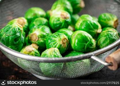 Brussels sprouts in a colander. Against a dark background. High quality photo. Brussels sprouts in a colander.