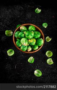 Brussels sprouts in a wooden bowl. On a black background. High quality photo. Brussels sprouts in a wooden bowl.