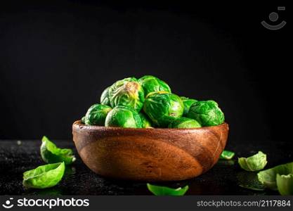 Brussels sprouts in a wooden bowl. On a black background. High quality photo. Brussels sprouts in a wooden bowl.