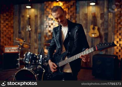 Brutal guitarist with electric guitar, music performing on stage. Rock band performance or repetition in garage, man with string musical instrument, live sound performer. Brutal guitarist with electric guitar on stage