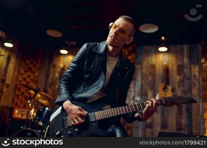 Brutal guitarist with electric guitar, music performing on stage. Rock band performance or repetition in garage, man with string musical instrument. Brutal guitarist with electric guitar on stage