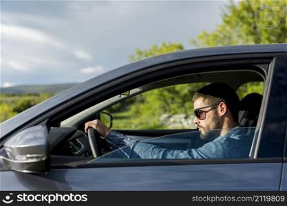 brutal male with sunglasses driving car