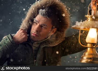 Brutal man walking under snowstorm at night lighting his way with lantern