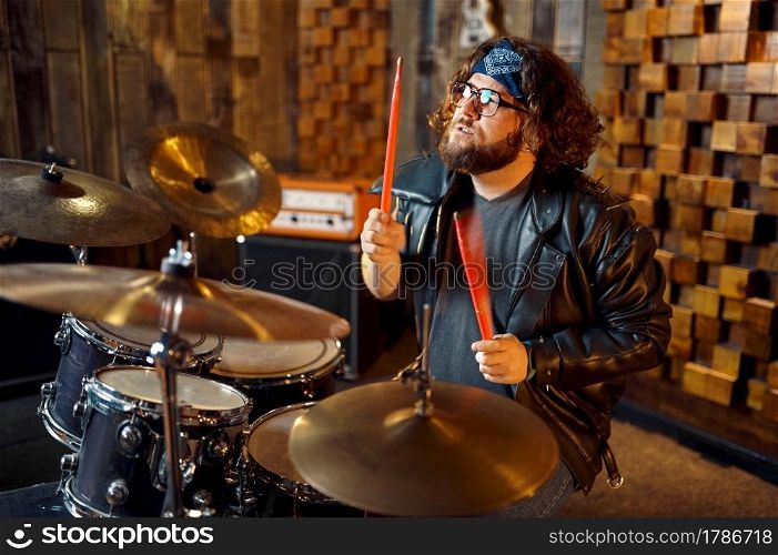 Brutal musician behind the drum kit, music performing on stage. Rock band performance or repetition in garage, man with musical instrument, live sound performer. Brutal musician behind the drum kit on stage