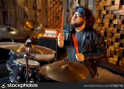 Brutal musician behind the drum kit, music performing on stage. Rock band performance or repetition in garage, man with musical instrument, live sound performer. Brutal musician behind the drum kit on stage
