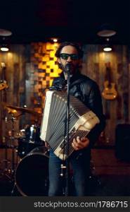 Brutal musician with accordion, music performing. Rock band performance or repetition, man with musical instrument, live sound. Brutal musician with accordion, music performing