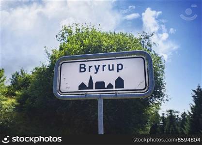 Bryrup city sign with green trees and blue sky in the background