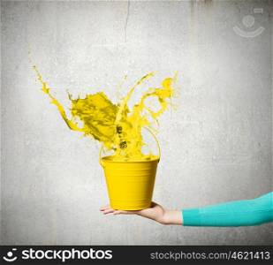 Bucket in hand. Close up of woman hand holding bucket with colorful splashes