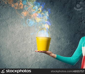 Bucket in hand. Close up of woman hand holding yellow bucket