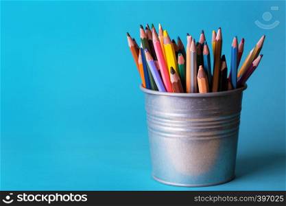 bucket with colorful pencils on a blue background