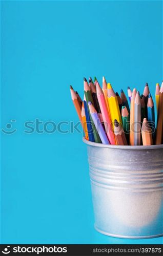 bucket with colorful pencils on a blue background