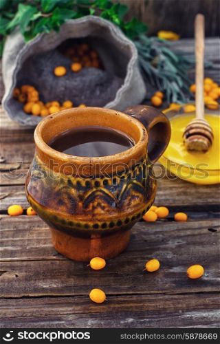 buckthorn. Clay mug with medicinal decoction of sea buckthorn and honey