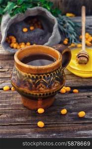 buckthorn. Clay mug with medicinal decoction of sea buckthorn and honey
