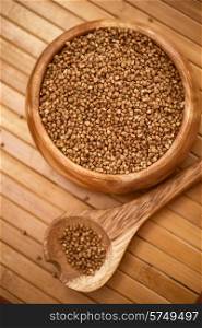 buckwheat at wooden plate on wooden background. buckwheat