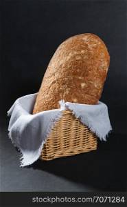 buckwheat bread in a wicker basket with a napkin on dark background