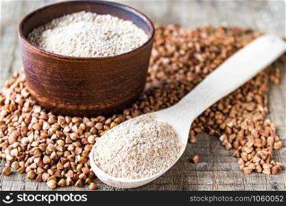 Buckwheat flour in a bowl near the buckwheat grain and a spoon with flour. A pile of buckwheat flour. Close-up.. Buckwheat flour in a bowl near the buckwheat grain and a spoon with flour. A pile of buckwheat flour.