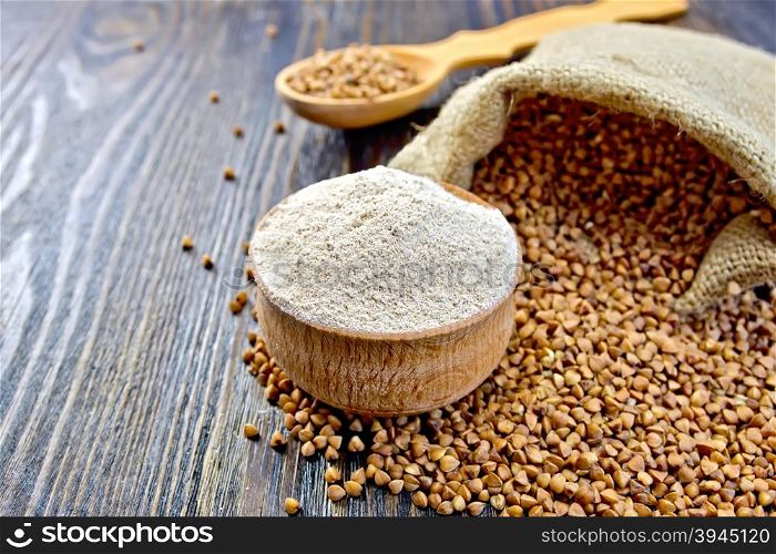 Buckwheat flour in a wooden bowl, buckwheat in a bag on a wooden boards background