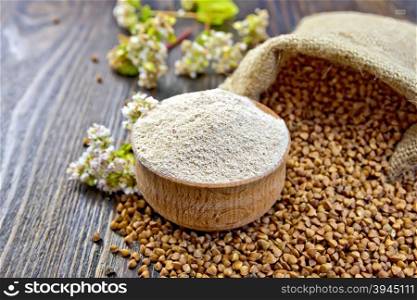 Buckwheat flour in a wooden bowl, buckwheat in the bag, buckwheat flower on the background of wooden boards
