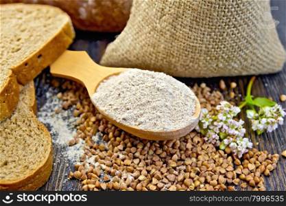 Buckwheat Flour in spoon, buckwheat in the bag on the table, slices of bread, buckwheat flower on the background of wooden boards