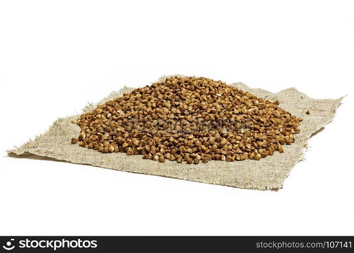 Buckwheat groats lie on a cloth napkin on a white background