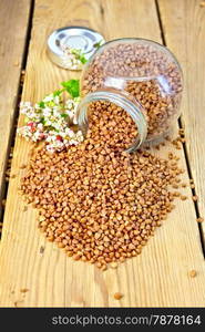 Buckwheat in a glass jar and on the table, flower buckwheat on a wooden boards background