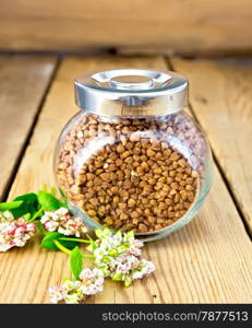 Buckwheat in a glass jar, flower buckwheat on a wooden boards background