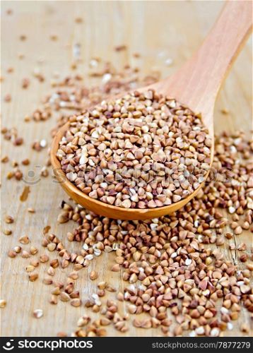 Buckwheat in a wooden spoon on a wooden boards background