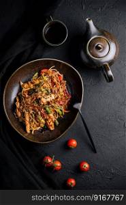 Buckwheat noodle in a black bowl on chicken fillet with tea