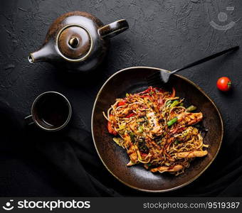 Buckwheat noodle in a black bowl on chicken fillet with tea