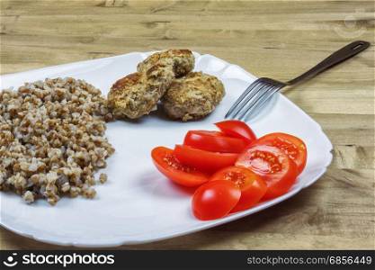 Buckwheat porridge with meat cutlets and red tomatoes