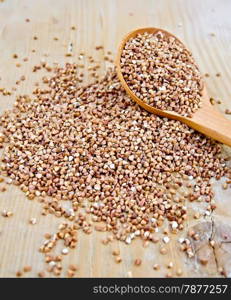 Buckwheat with a spoon on a wooden boards background