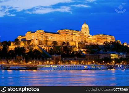 Buda Castle by the Danube river, illuminated at dusk in Budapest, Hungary.