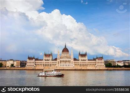 Budapest Parliament building in Hungary, Danube river with passenger boat and dramatic sky.
