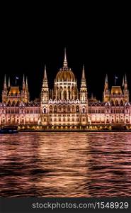 Budapest Parliament in Hungary at night, reflections on the Danube river waters.. Budapest Parliament building in Hungary at twilight.